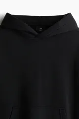 Canguro negro con capucha, corte holgado y bolsillo tipo canguro. Confeccionado en tejido de mezcla de algodón con interior cepillado suave. Remate acanalado en puños y bajo.