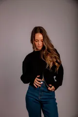 Buzo gris de punto con cuello redondo, mangas largas abullonadas y cierre frontal asimétrico.