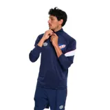 Buzo deportivo Umbro del Club Nacional de Football, modelo Training Half Zip. Color rojo con detalles en azul y blanco en mangas y cuello.