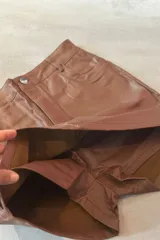 Short pollera negro de simil cuero, con cierre frontal y calce ajustado.