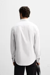 Camisa celeste de corte slim fit, confeccionada en tejido de algodón. Tiene cuello italiano, mangas largas con puños abotonados y cierre frontal con botones.