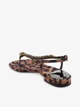 Sandalia color bronce con tira en el dedo y diseño entrelazado con apliques de strass. Cuenta con pulsera ajustable en el talón y una base plana de leve altura.