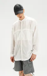 Camisa blanca de manga larga con cuello mao y bolsillos frontales.