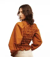 Blusa blanca de algodón con frunces tipo smock en el cuerpo, cuello redondo y mangas largas abullonadas con puños elásticos.