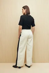 Pantalón de jogging color crema con cintura elástica, cordón ajustable y franja lateral negra.
