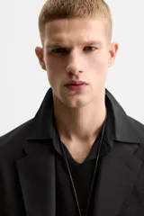 Blazer negro de lana con cuello de solapa de muesca, corte recto, manga larga con puños abotonados, bolsillos de vivo en el pecho y de solapa en la cadera, abertura en la parte posterior y cierre frontal con botones. Colección Origins.