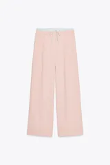 Pantalón de tiro alto color rosa pálido, con cintura combinada a contraste tipo bóxer y cordones ajustables. Tiene pinzas en el delantero, bolsillos laterales y falsos bolsillos de vivo en la espalda.