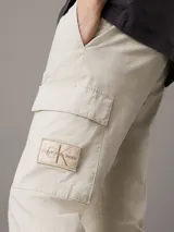 Pantalón cargo color beige de corte skinny, con cintura y puños elásticos, cierre de cremallera y botón de presión, bolsillos delanteros y traseros, bolsillos cargo con solapa, acabado ligeramente lavado e insignia con el monograma de Calvin Klein en la pierna.