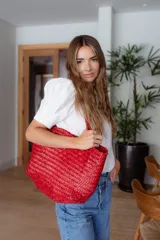 Bolso tipo tote de cuero vacuno, completamente trenzado a mano. El color es marrón oscuro, casi chocolate. Posee dos asas de hombro trenzadas.