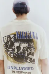 Remera color crema de corte holgado con cuello redondo y estampado frontal con el logo de la banda Nirvana y la frase 'Unplugged in New York' en color azul.