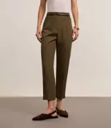 Pantalón de vestir azul marino, de corte zanahoria, con cinturón fino negro con hebilla dorada.