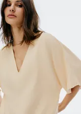 Blusa color crema con escote en V y mangas cortas amplias.