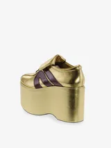 Zapatilla deportiva con plataforma extragrande, color plateado metálico con efecto arrugado en la plataforma y acabado brillante en el cuerpo. Presenta tres franjas laterales en azul marino brillante y cordones azules.