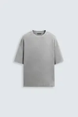 Camiseta gris de algodón con cuello redondo, manga corta y corte holgado. Tiene un efecto lavado que le da una apariencia única.