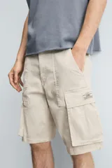 Bermuda cargo de algodón color marrón oscuro, tiro medio, corte regular, con bolsillos laterales de parche con solapa y bolsillos traseros de vivo.