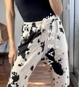 Pantalón largo de lanilla color crema con estampado de manchas de vaca en negro, corte recto y cintura con cordón ajustable.