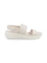 Sandalias Hush Puppies color hueso con doble tira ancha sobre el empeine, ajuste con velcro en el talón y suela de plataforma baja.