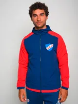 Campera deportiva con capucha, azul con mangas y hombros rojos, cierre frontal y escudo del Club Nacional de Football en el pecho.