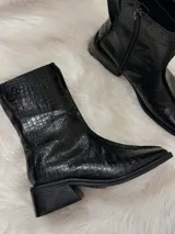 Bota negra de caña media con textura de cocodrilo, punta cuadrada y tacón bajo.
