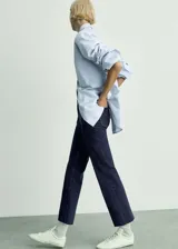 Jeans de tiro medio color azul oscuro, con diseño acampanado, bolsillos de parche delanteros y traseros, y cierre frontal con cremallera y botón.