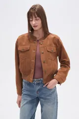 Campera estilo bomber corta de gamuza color marrón, con cuello redondo, cierre frontal de botones y dos bolsillos de parche con solapa en el pecho. Presenta puños y cintura elásticos.
