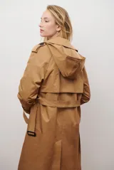 Trench coat largo color beige con doble botonadura, cuello solapa, cinturón ajustable y puños con tiras.