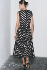 Vestido midi negro con estampado de lunares blancos, cuello redondo y sin mangas.