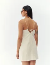 Vestido corto color crema con breteles finos y corte recto.