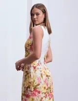Vestido corto sin mangas, de crepe con estampado floral en tonos amarillo, rosa y verde sobre fondo blanco. Tiene cuello redondo, espalda con abertura central y cierre invisible.
