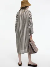 Vestido largo de manga larga con botones en el escote y tajos verticales laterales. Diseño a rayas verticales en tonos marrón y blanco.