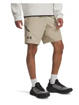 Short deportivo Under Armour Unstoppable para hombre, color beige, con logo negro en la pierna izquierda y cierre lateral en negro.