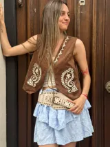 Chaleco marrón con bordado floral blanco, escote en V y cierre frontal con botones.