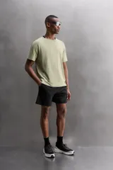 Camiseta deportiva verde militar confeccionada en tejido estructurado, ligero y elástico. Tiene cuello redondo, manga corta y bajo con aberturas laterales. Incluye logo estampado en el bajo.