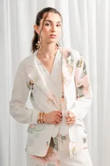 Blazer de lino blanco con estampado floral en tonos rosa y verde, corte holgado, cuello solapa y bolsillos laterales.