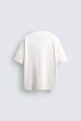 Camiseta blanca de corte holgado con cuello en V y mangas cortas. Presenta un diseño de malla con diferentes texturas combinadas a tono y estampado frontal con la inscripción "Legacy Crew 95 Elite Mode".