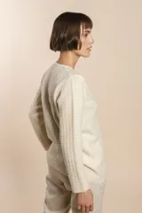 Cardigan tejido con efecto fantasia color crema. Una prenda de silueta amplia y cómoda. Tejido en 100% lana fina sin teñir.