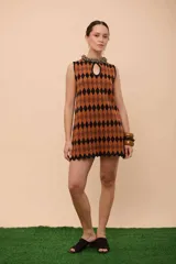 Vestido corto sin mangas con estampado de rombos en tonos marrón y negro, escote gota y ruedo con terminación en picos.