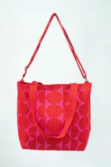 Bolso tipo tote con estampado de círculos rojos y rosados, doble asa corta y correa larga extraíble.