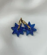 Aros colgantes con forma de estrella azul con glitter, unidos a un aro dorado.