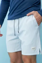 Short de baño celeste con rayas verticales blancas, cordón ajustable en la cintura y etiqueta con logo en la pierna.