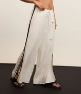 Pantalón de playa de lino y viscosa color blanco, con rayas laterales a contratono, cintura elastizada y lazo ajustable.