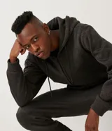 Campera de algodón gris oscuro jaspeado, con cierre frontal de cremallera, capucha con cordones trenzados y bolsillo canguro.