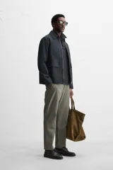 Pantalón chino negro slim fit confeccionado en tejido técnico de secado rápido. Cuenta con bolsillos frontales y traseros de vivo. Cierre frontal con cremallera y botón.