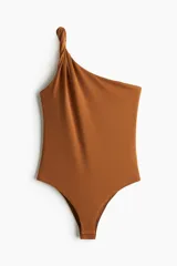 Body marrón de punto elástico con escote asimétrico y un tirante torneado. Tiene botones a presión ocultos en la entrepierna y está completamente forrado.
