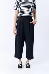 Pantalón negro de corte ancho, con pinzas en la cintura y bolsillos laterales.