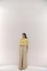 Chaqueta de punto color amarillo con textura, cuello redondo, manga francesa, bolsillos delanteros y cierre frontal con botones dorados.