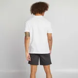 Conjunto de pijama corto para hombre, compuesto por una remera blanca con el logo de Marvel en rojo y un short gris oscuro.
