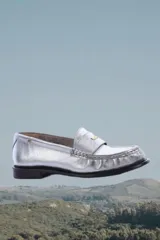 Mocasín de cuero plateado con textura croco y diseño formal.