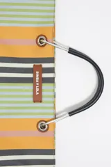 Bolso tote de tela a rayas verticales en tonos verde oliva, lila, blanco y rosa. Tiene doble asa de mano de cuero marrón y logo de la marca en etiqueta de cuero.