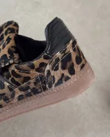 Zapatillas deportivas de cuero vacuno con estampado animal print de vaca en blanco y marrón.